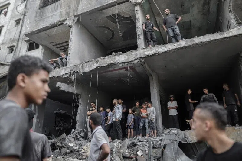 Palestinians in the remains of a destroyed building following an Israeli airstrike at the Al-Shati refugee camp in Gaza City, northern Gaza, on Oct 29.