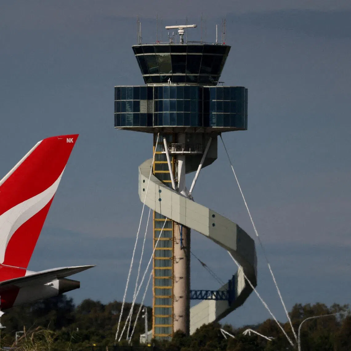 A Qantas plane passes an air-traffic control tower as it taxis along a runway at  Sydney Airport.