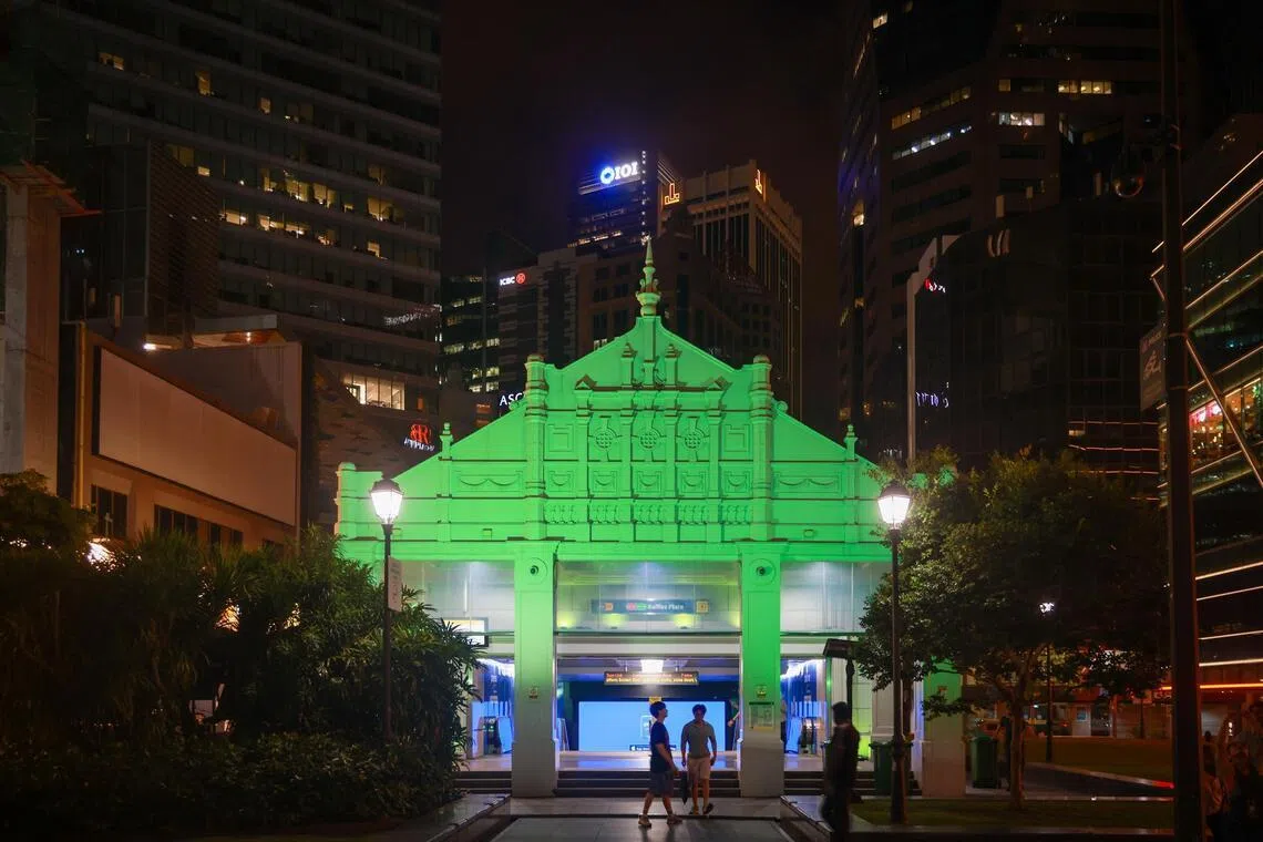 The facade of Raffles Place MRT station bathed in green on June 26.