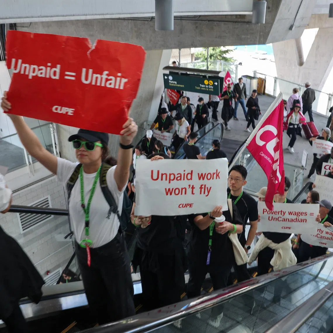 FILE PHOTO: Demonstrators display placards while riding an escalator as Air Canada flight attendants said they will remain on strike and challenge a return-to-work order they called unconstitutional, defying a government decision to force them back to their duties, at Vancouver International Airport in Richmond, British Columbia, Canada, August 17, 2025.  REUTERS/Chris Helgren/File Photo