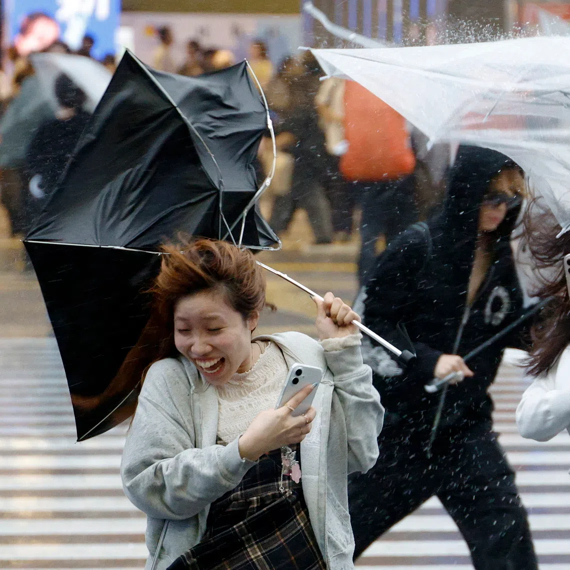 epa13253937 A young woman struggles to handle her umbrella under heavy rain and wind triggered by Typhoon Dujuan near Shinjuku station in Tokyo, Japan, 21 September 2026. Powerful and large Typhoon Dujuan approached the Boso Peninsula, Chiba Prefecture, near Tokyo, bringing heavy rain and disturbing transportation. EPA/FRANCK ROBICHON