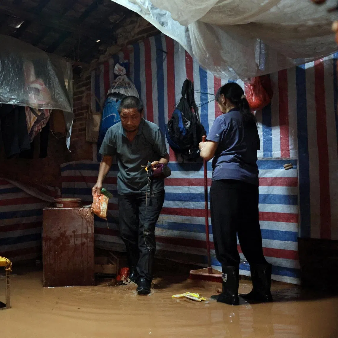 A resident moves his belongings in a flooded house after days of heavy rainfall in August 2025 in Qingyuan, Guangdong.