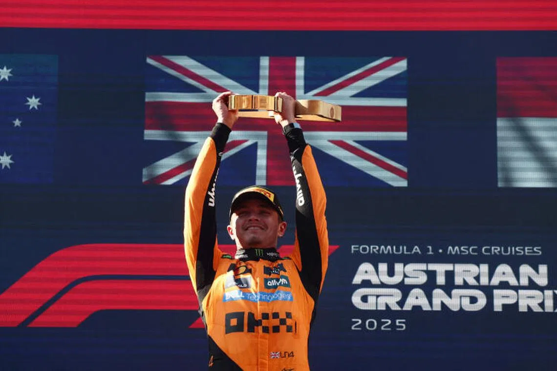 McLaren's Lando Norris celebrates on the podium with a trophy after winning the Austrian Grand Prix.
