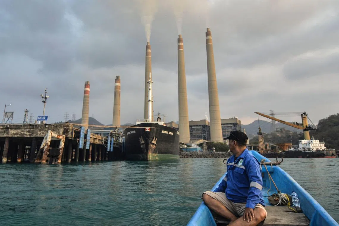 This picture taken on October 31, 2023 shows a fisherman looking at the Suralaya coal-fired power plant in Cilegon, Indonesia's Banten province. As countries gather in Dubai for crunch climate talks, the future of polluting fossil fuel coal will be high on the agenda. For some, the age of coal is now clearly over, and Indonesia has committed to moving away from the fuel despite being the world's top exporter. (Photo by Ronald SIAGIAN / AFP) / To go with AFP story Climate-UN-COP28-UAE-Indonesia-coal,FOCUS by Dessy SAGITA and Marchio GORBIANO