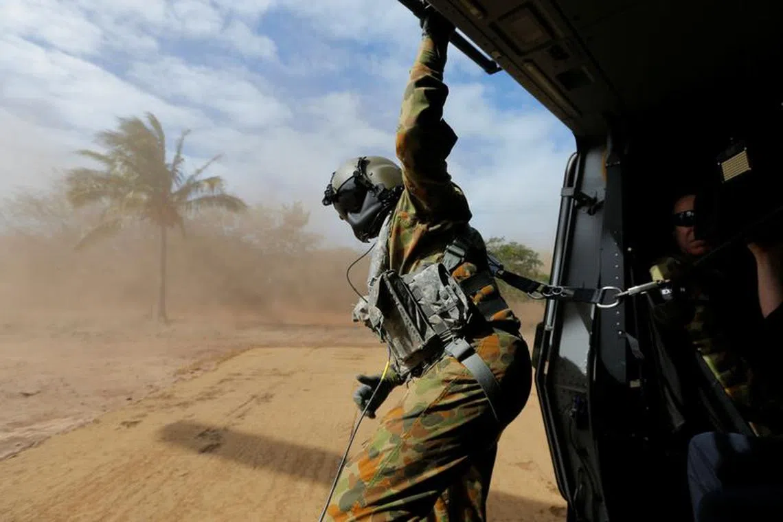 A crewman aboard an Australian Army MRH-90 helicopter leans out of the aircraft as it kicks up sand upon landing at Langham Beach during Talisman Saber joint military exercises between Australia and the United States in northeast Australia, July 13, 2017.  REUTERS/Jason Reed/File Photo