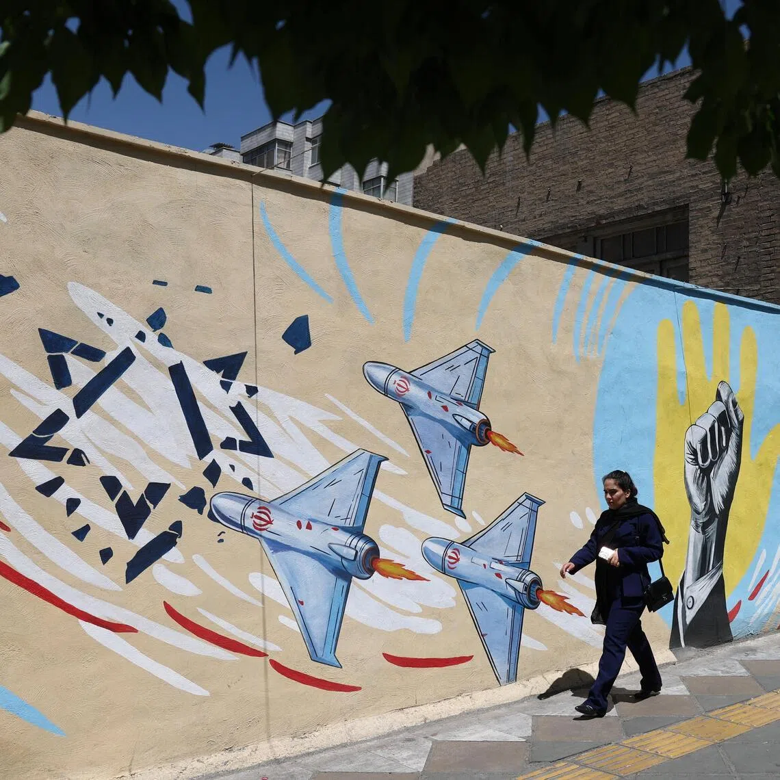 An Iranian woman walking next to an anti-Israeli mural on a street in Tehran on May 30