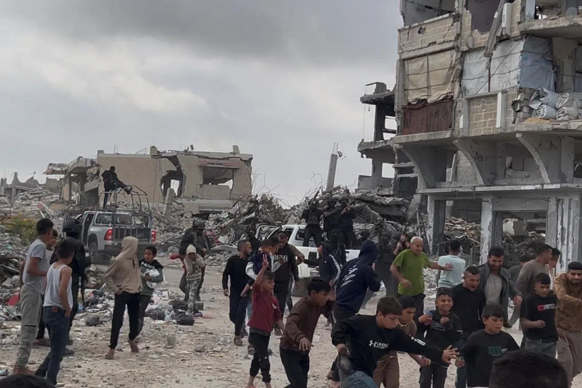 People react near Palestinians fighters after clashes with Israeli-backed militia, in Khan Younis, in the southern Gaza Strip, on April 20.