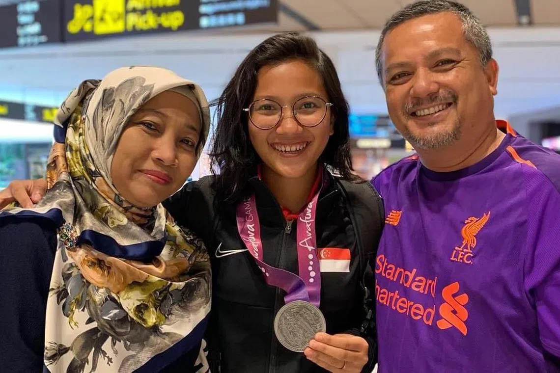 dlmemory14 - After returning home with a silver medal from the 2019 Arafura Games in Darwin, Australia, Singapore women's football team forward Izzati Rosni (centre) poses with her father Rosni Hashim and her late mother Nor Aishah.



Credit: Courtesy of Izzati Rosni