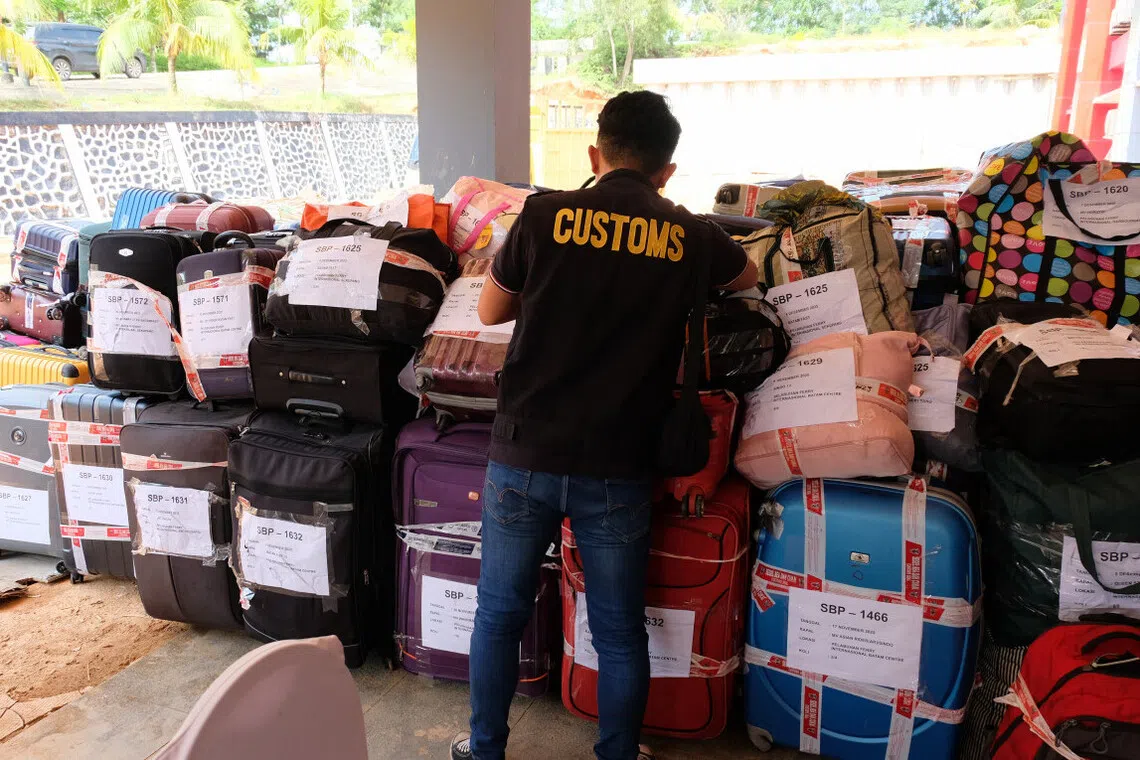 An officer with the Batam Customs and Excise Office inspects luggage containing used clothing on Dec 10.