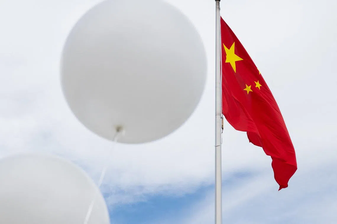 Two white balloons float near the Chinese flag as activists protests against the Chinese government over the alleged Chinese surveillance balloon that was shot down over the US last week.