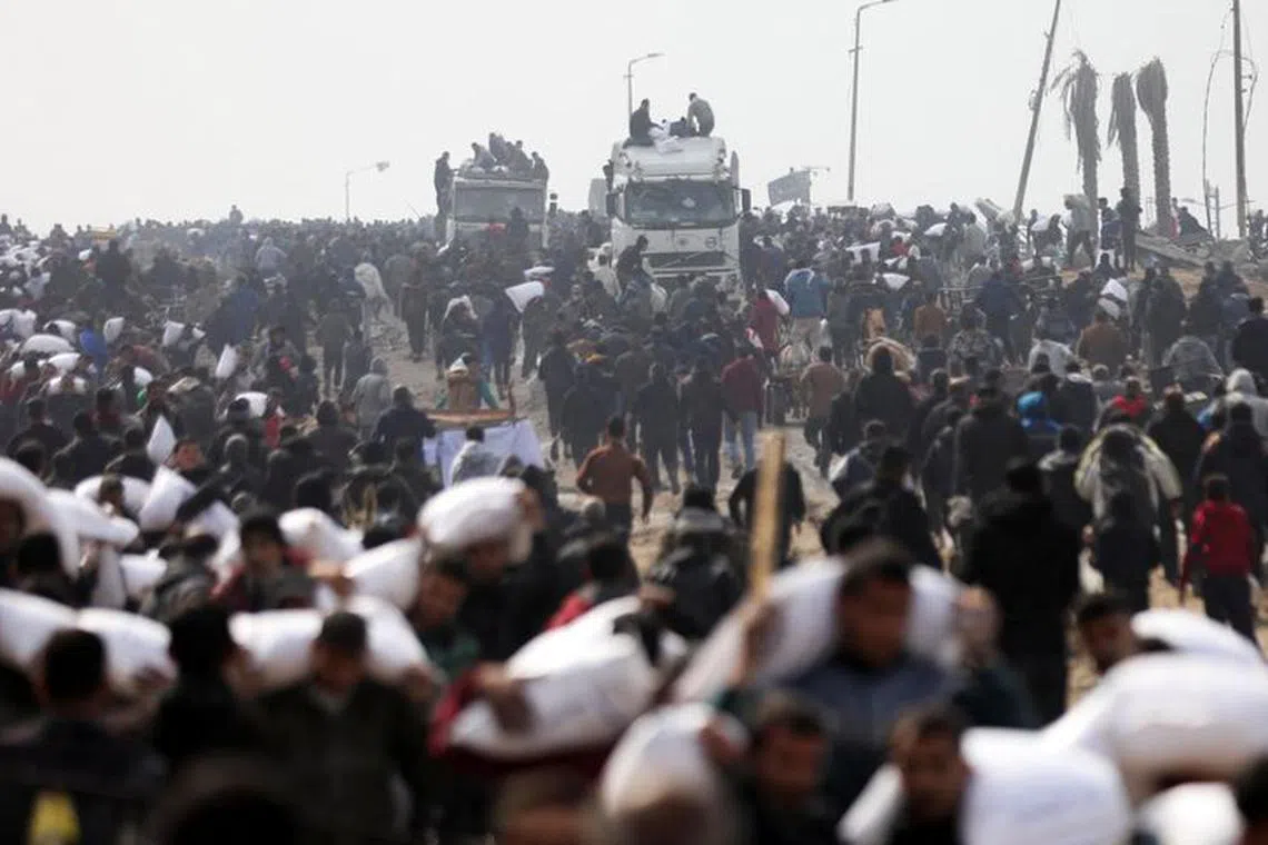 Palestinians carry bags of flour they grabbed from an aid truck near an Israeli checkpoint. 