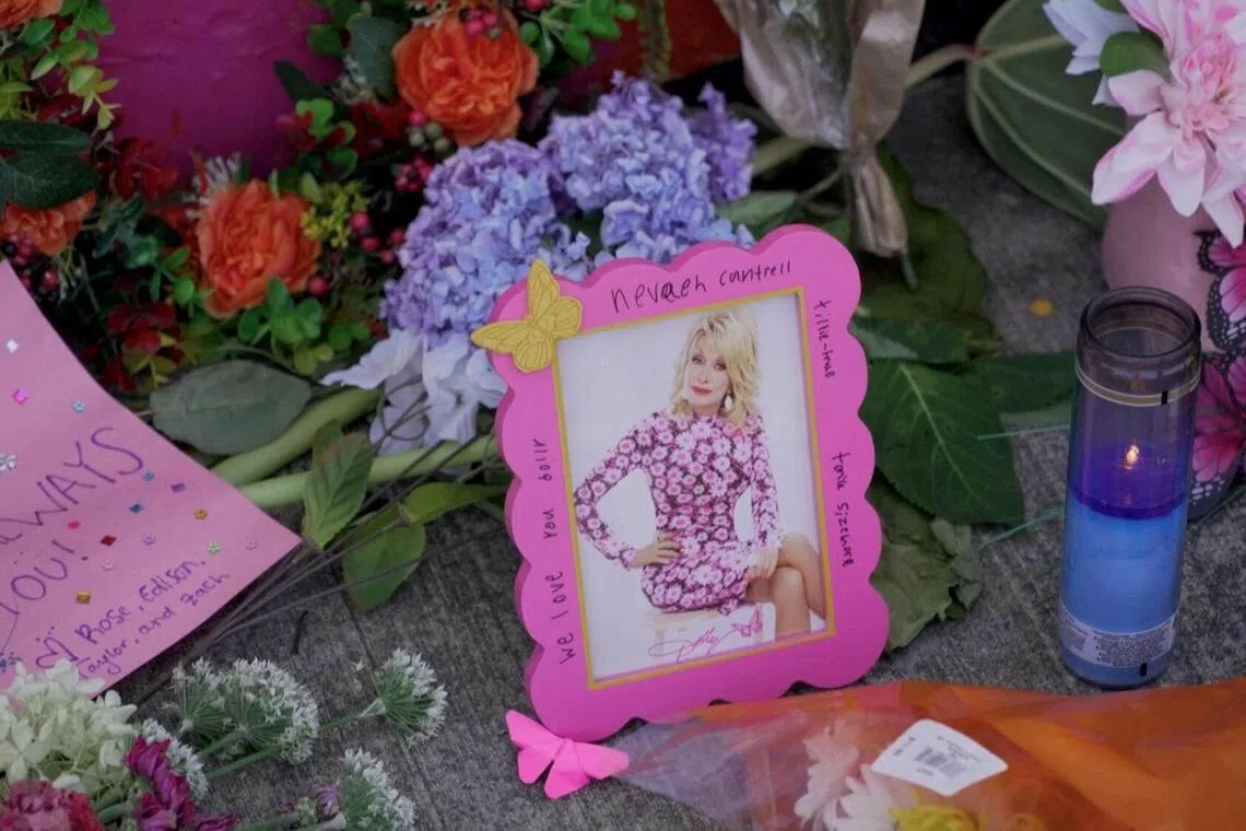 Flowers and signs are left in front of a mural of Dolly Parton in Ringgold, where the country music star married Carl Dean, in Georgia, US.