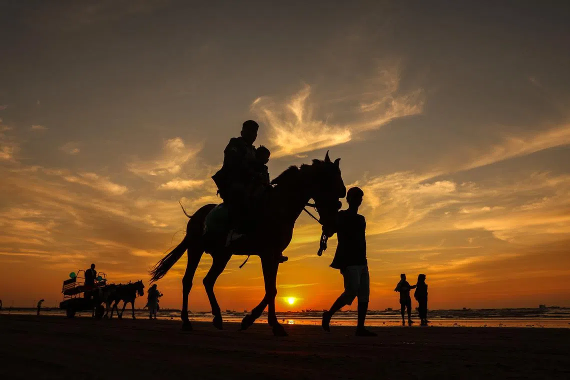 People riding a horse along Gorai Beach at sunset, in Mumbai, India, on Dec 9, 2024.  