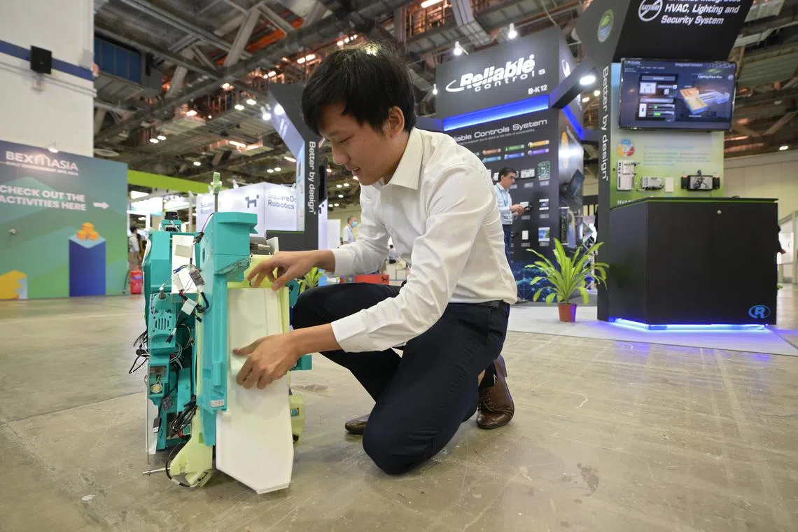 Fabrica.AI's co-founder Keefe Wayne Teo with the company's tile-grouting robot at BEX Asia. The robot is said to do the work of five people, grouting and cleaning tile gaps at the press of a button.
