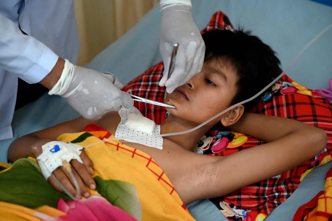 This photo taken on February 10, 2025 shows a nurse cleaning a wound of Yeat Saly, who was injured in a mortar bomb explosion, in bed at a Chinese-funded hospital in Tboung Khmum province. Parts of Cambodia are still littered with unexploded ordnance from decades of conflict, and US President Donald Trump's decision to freeze virtually all American aid has seen many long-running projects to clear the deadly debris grind to a halt. (Photo by TANG CHHIN Sothy / AFP) / To go with 'CAMBODIA-US-POLITICS-LANDMINE-AID,FOCUS' by Suy SE