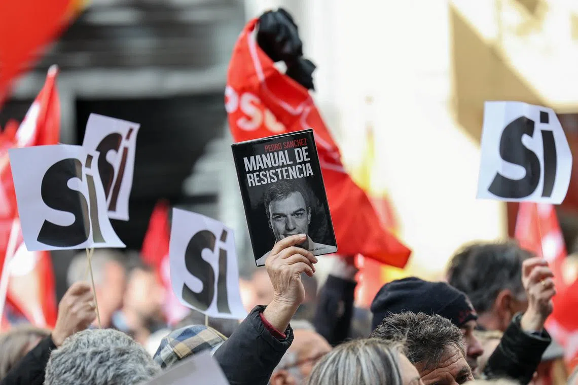 A person holds a copy of the book \"Resistance manual\" by Secretary General of PSOE and Prime Minister Pedro Sanchez, as people gather outside Spain's Socialist Party (PSOE) headquarters to show support for Sanchez, in Madrid, Spain April 27, 2024. REUTERS/Violeta Santos Moura