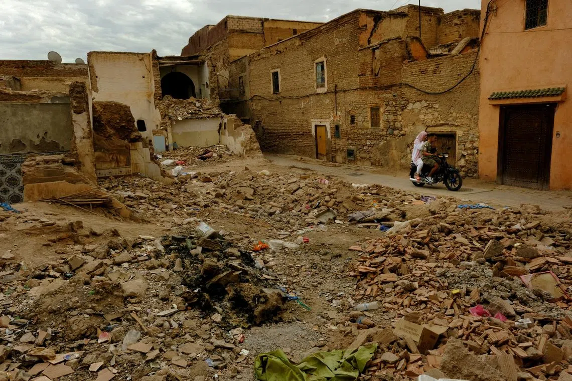 FILE PHOTO: People ride a motorcycle past damaged buildings in the \"Mellah\", or Jewish quarter, in the aftermath of last month's deadly earthquake, in Marrakech, Morocco, October 15, 2023. REUTERS/Susana Vera/File Photo