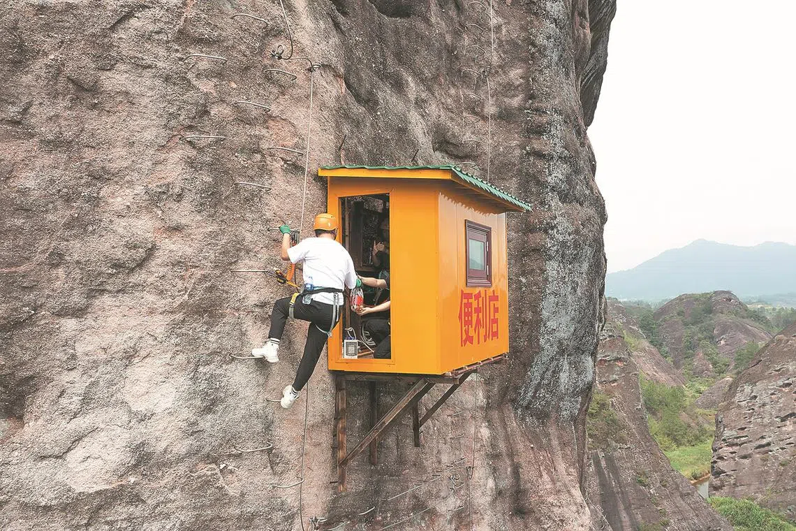 A climber shopping at a convenience store built on a cliff at the Shiniuzhai scenic area in China's Pingjiang county.