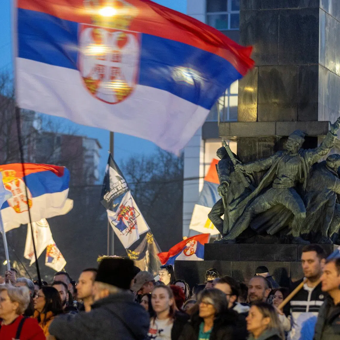 People hold flags during a student-led demonstration to mark one year since a major anti-government rally and to protest against authorities over corruption and accountability, in Nis, Serbia, March 1, 2026. REUTERS/Djordje Kojadinovic