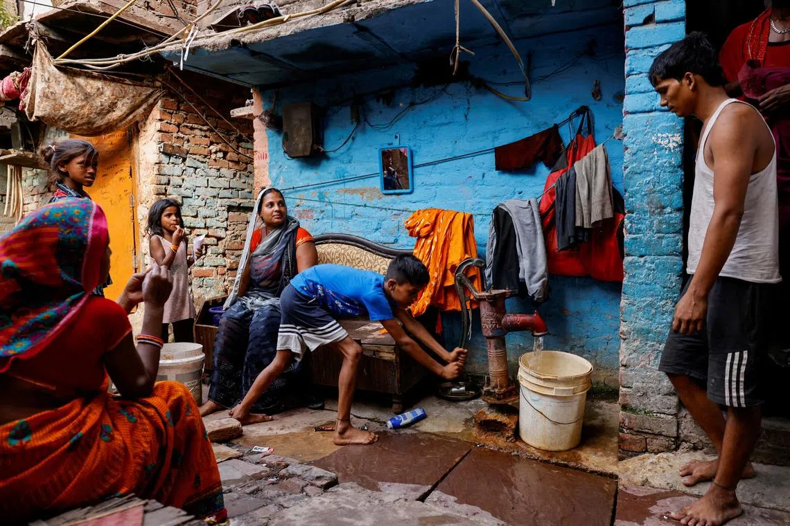 FILE PHOTO: A boy fills water in a container using a hand pump on a hot summer day during a heatwave in New Delhi, India, June 3, 2024. REUTERS/Anushree Fadnavis/File Photo