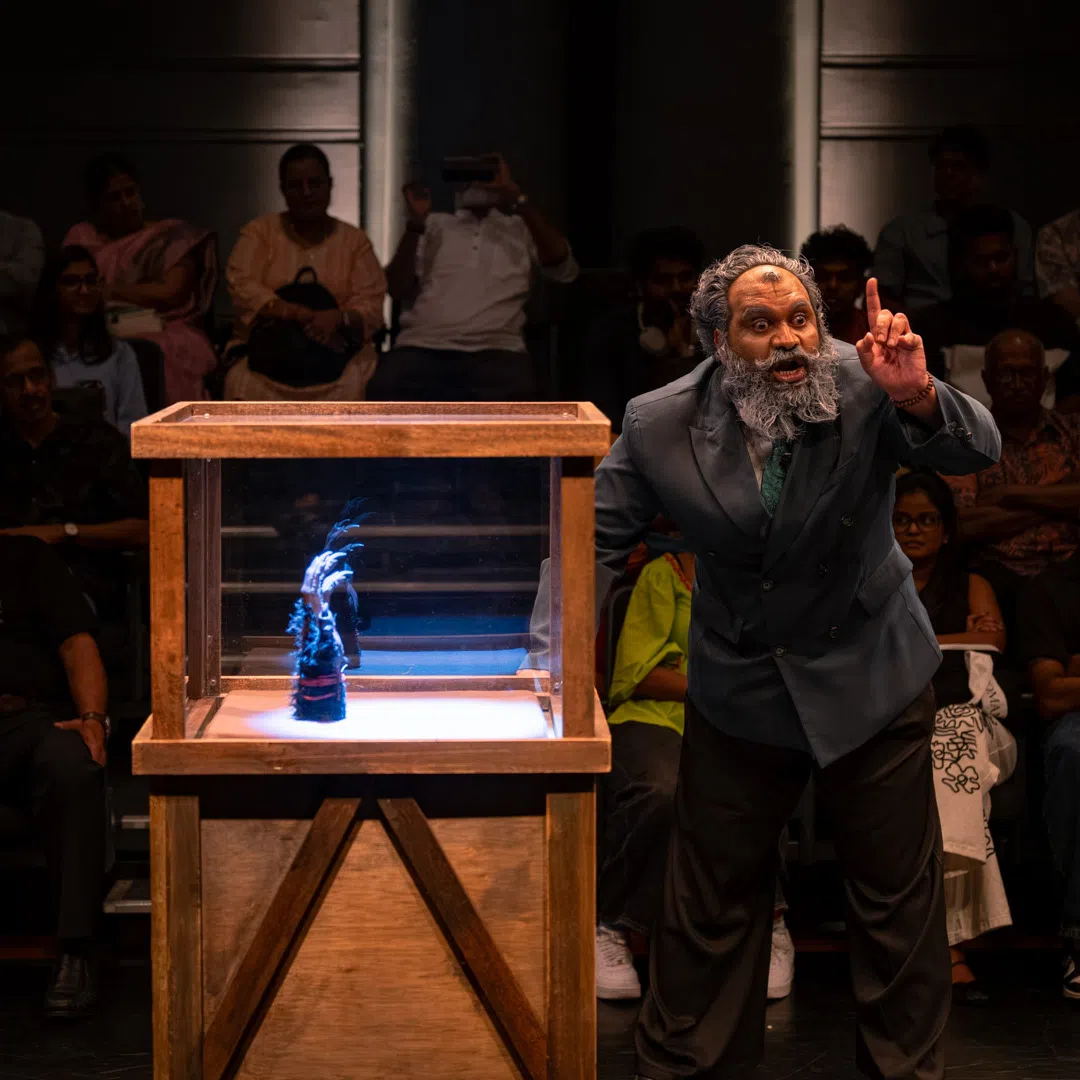 Karls Karthikeyan lolls his tongue and jerks his head as an eccentric senior historian.