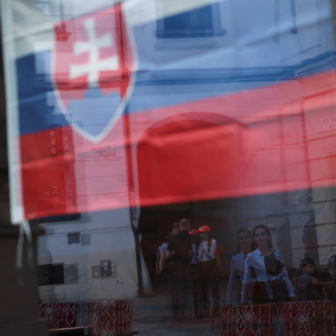 People are reflected in a window adorned with a Slovakian flag in Bratislava, Slovakia, May 18, 2024. REUTERS/Claudia Greco