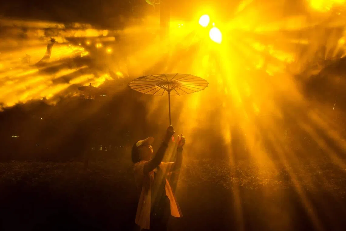 TOPSHOT - A woman holding an umbrella poses for a picture as she visits the Shanghai International Light Festival in a park in Shanghai on September 17, 2026. (Photo by CN-STR / AFP) / China OUT