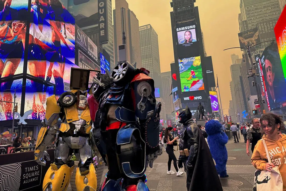 People wearing costumes as they walk in Times Square as Manhattan is shrouded in haze and smoke which drifted south from wildfires in Canada, in New York City, on June 7, 2023. 