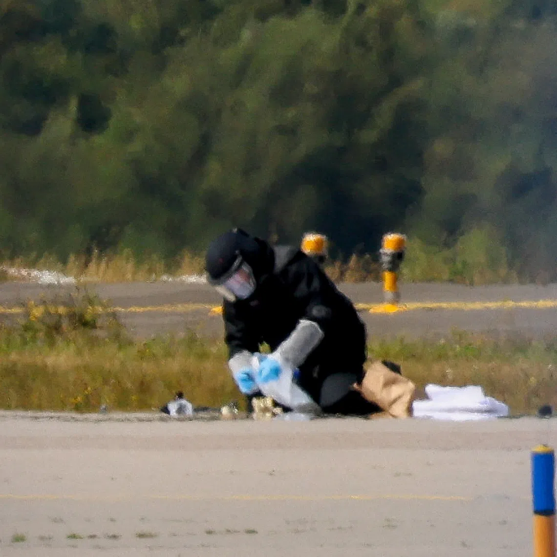 FILE PHOTO: A police officer in protective clothing works at Leipzig/Halle Airport in Schkeuditz, Germany, August 5, 2026, after the police said explosives experts examined a drone near a runway, and after a DHL cargo aircraft hit an unknown object as it was climbing away from the airport overnight, prompting an unscheduled landing in Hanover, according to a source familiar with the incident. REUTERS/Axel Schmidt/File Photo