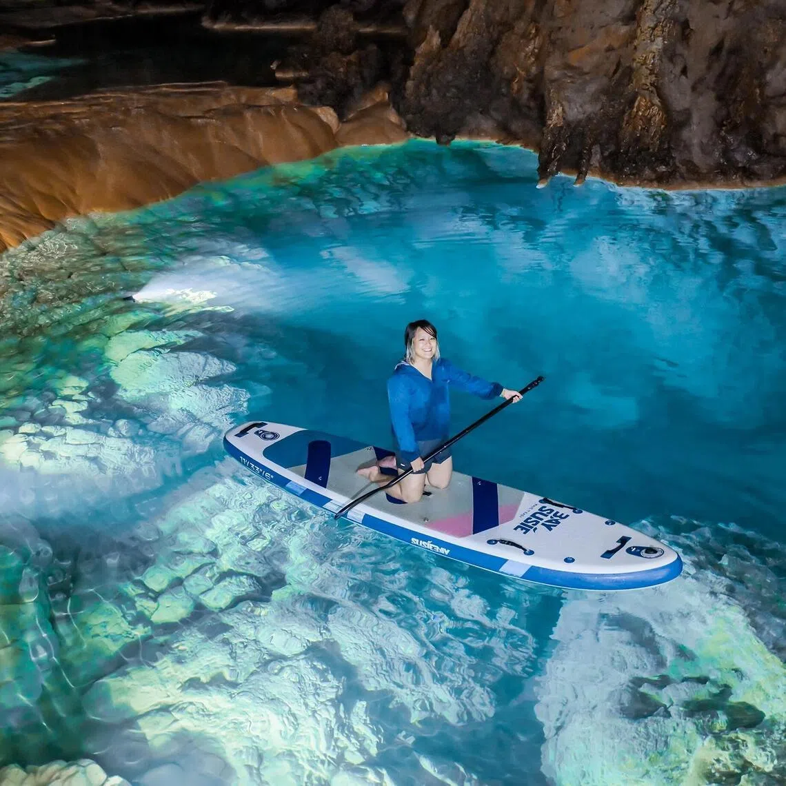 The writer tries stand-up paddleboarding in Shilong Cave, an hour from Guiyang — a highlight of Guizhou’s emerging cave tourism trend.