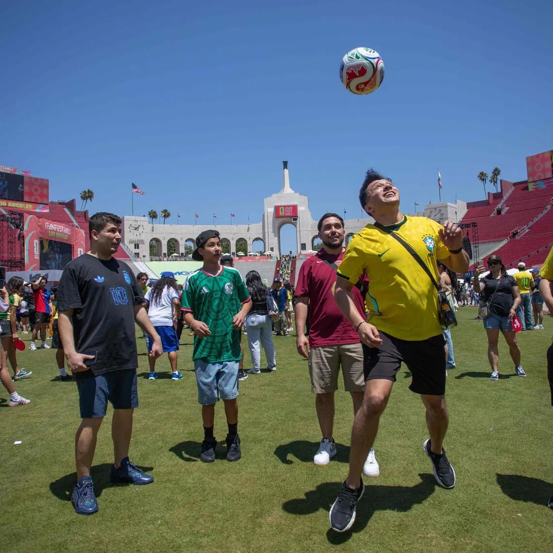 Brazil fans play football while people arrive for a watch party for the 2026 World Cup football tournament match between Brazil and Morocco at the FIFA Fan Festival at the LA Memorial Coliseum in Los Angeles on June 13, 2026.
