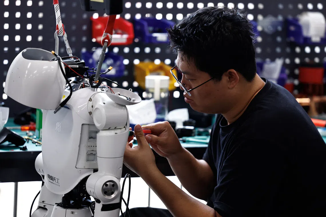 An engineer working on a Tiangong Omni humanoid robot in the research and testing area of the Beijing Humanoid Robot Innovation Centre.