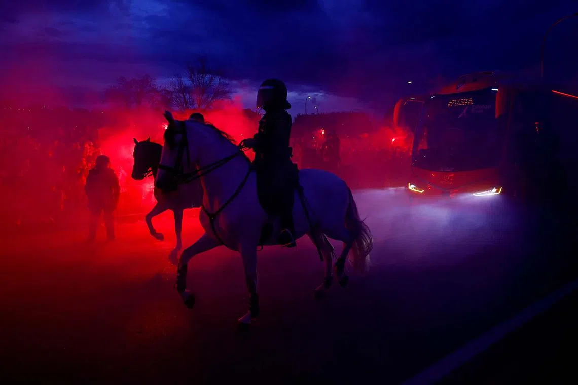 Police officers on horses patrolling as the Atletico Madrid team bus arrives outside the Metropolitano stadium in Madrid, Spain, before the Champions League soccer match between Atletico Madrid and Real Madrid on March 12, 2025.