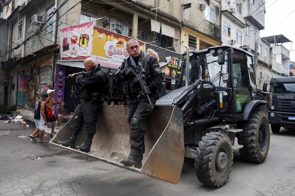 Police officers stand on a bulldozer during an anti-crime operation inside the favelas Mare complex.