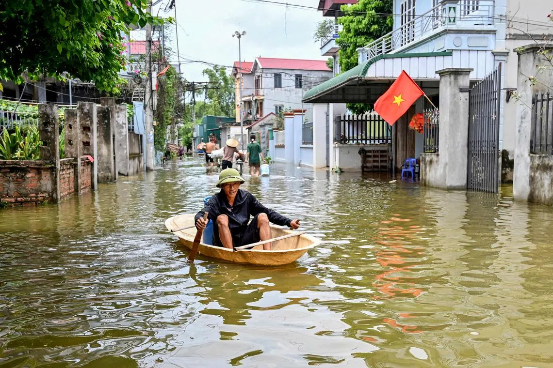 A man rowing a boat through flood waters in Ben Voi village on the outskirts of Hanoi, on July 28, 2024.