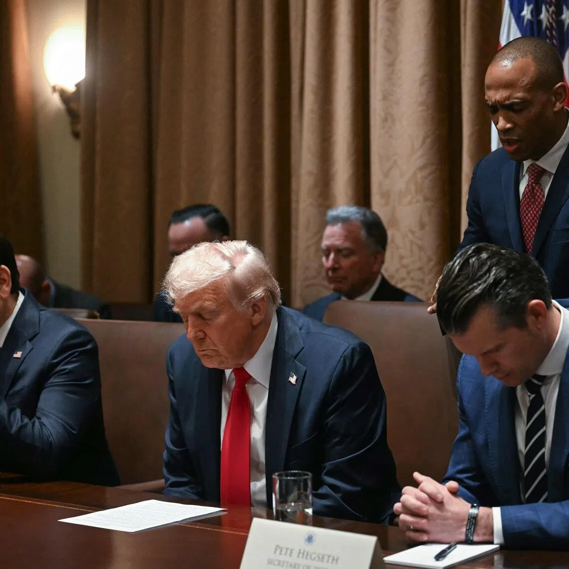 President Donald Trump bows his head in prayer alongside Secretary of State Marco Rubio and Defence Secretary Pete Hegseth during a Cabinet meeting.