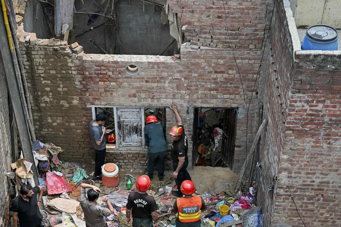Rescue personnel conduct a search operation amid rubble after the roof of a house collapsed in Lahore on July 30.