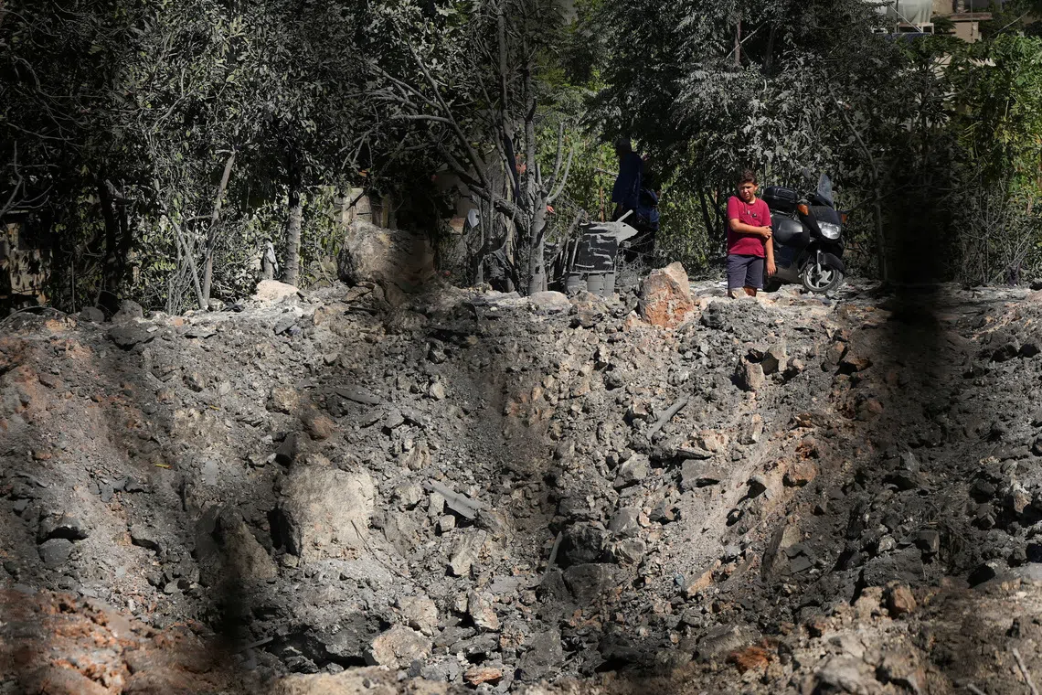 People and journalists stand at a site hit by Israeli strikes that occurred in the early hours of Thursday, according to Lebanon’s state news agency NNA, in Burj al-Shamali, southern Lebanon, August 6, 2026. REUTERS/Stringer