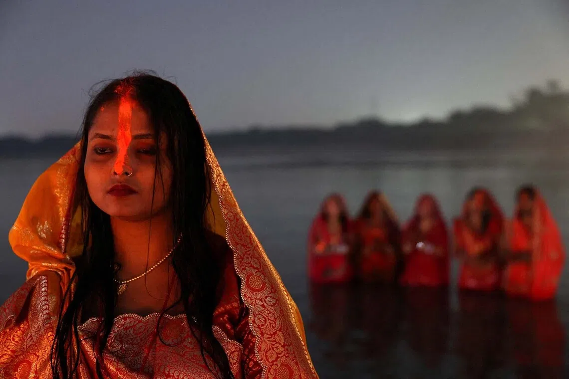 A Hindu woman with "sindhur", or vermilion powder, on her forehead stands in water as she worships the Sun god at the bank of the river Yamuna during the Hindu religious festival of Chhath Puja in Noida, India, October 28, 2025. REUTERS/Bhawika Chhabra TPX IMAGES OF THE DAY