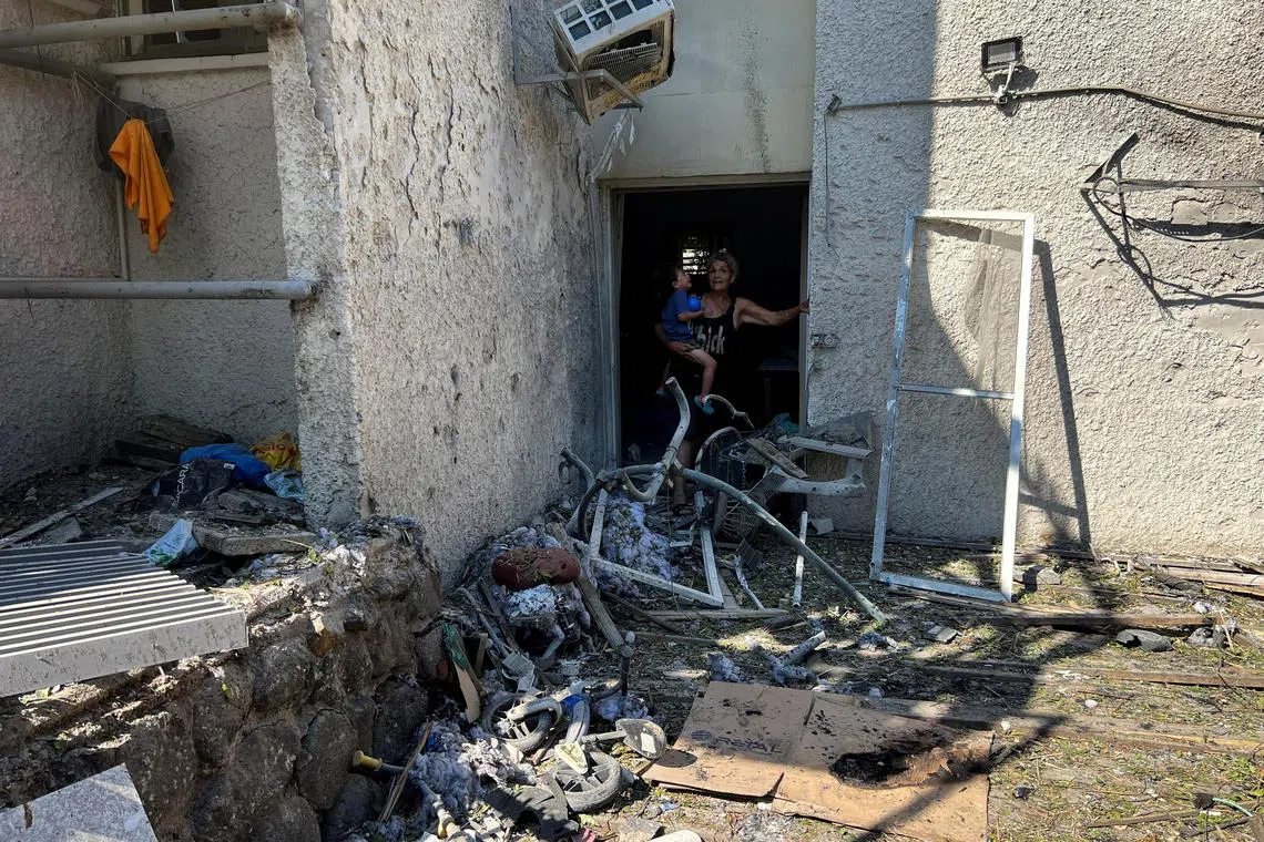 A woman holds a child at a house damaged after rockets were fired from Lebanon into the Israeli-occupied Golan Heights.