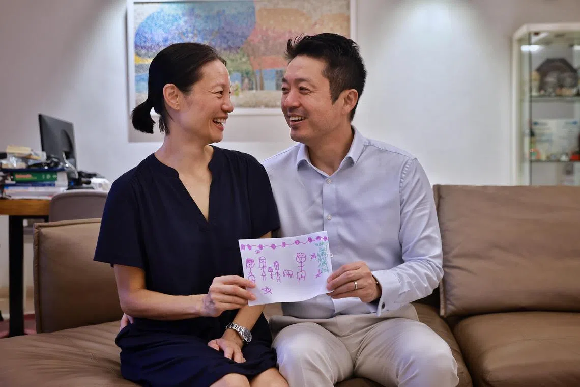 Vanessa Ping and Paul Pak, a couple who volunteer with Sanctuary Care, a respite care service for children in need, pose for a photo with a card given to them by one of the children they cared for.
