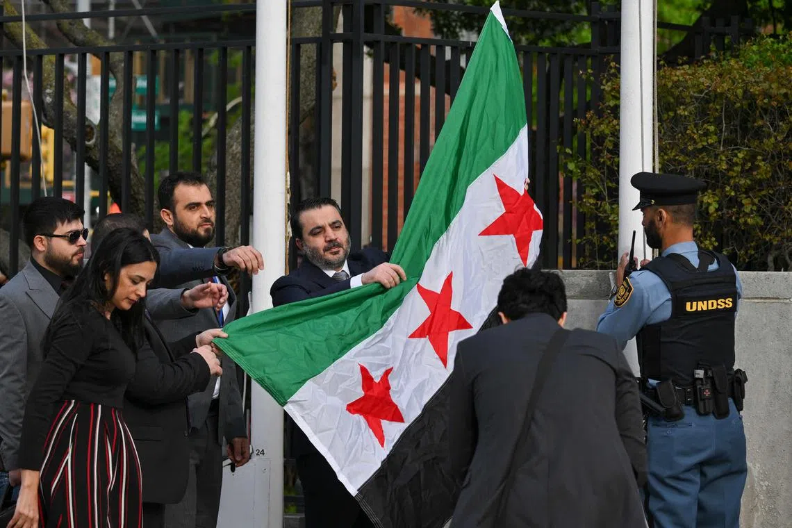 Syrian Foreign Minister Asaad al-Shaibani raising the new Syrian flag at the United Nations' headquarters in New York on April 25.