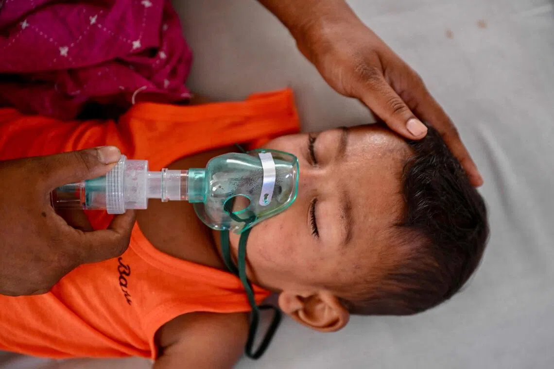A mother holds a nebulizer on the face of her child receiving treatment for measles in a paediatric ward at a hospital in Dhaka on April 9.