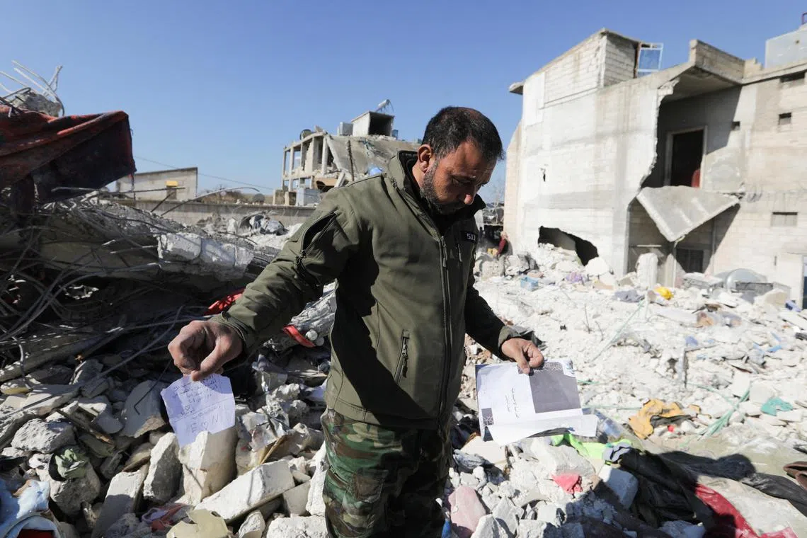 Quake survivor Naser al-Wakaa stands on the rubble of his damaged home, as he carries a scrap of paper showing writing by his daughter, Heba, who died in the aftermath of the earthquake.
