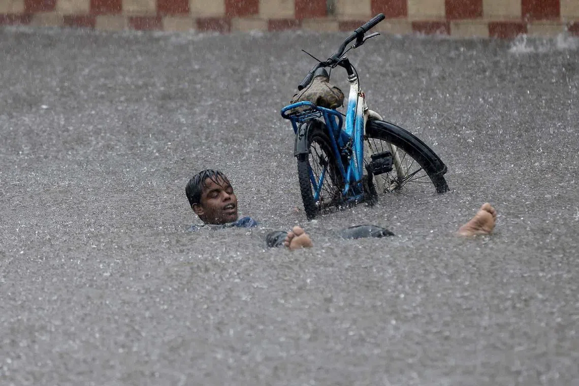 A boy plays on a flooded road amid heavy rainfall in Ahmedabad, India, Sept 17.