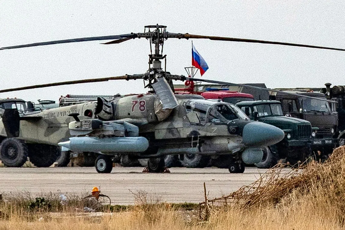A Russian military attack helicopter is pictured with other trucks and vehicles at an airbase in northeastern Syria on Dec 12.