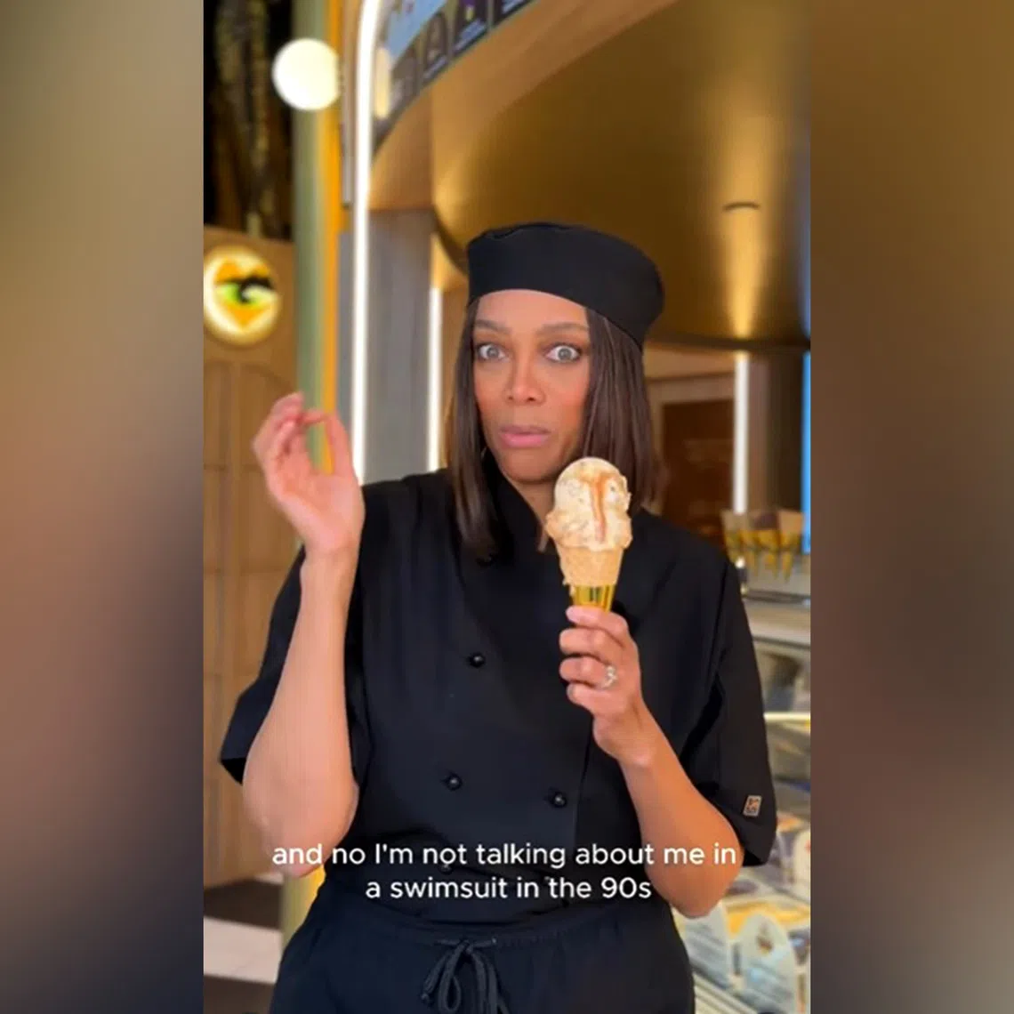 Tyra Banks at her Smize & Dream ice cream shop holding her hot ice cream flavour Hot Mama.