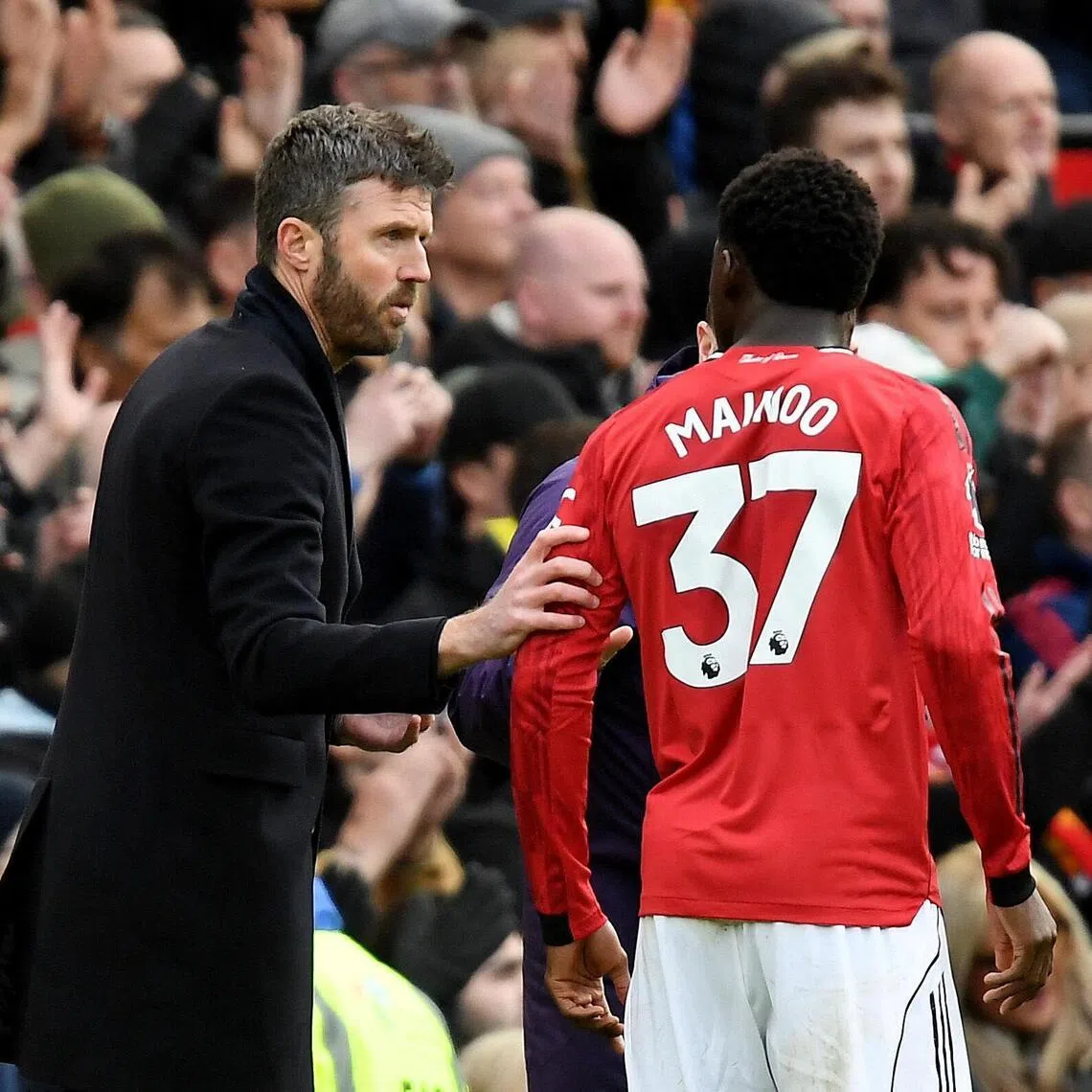 Manchester United interim manager Michael Carrick speaks to Kobbie Mainoo during a Premier League match against Aston Villa.