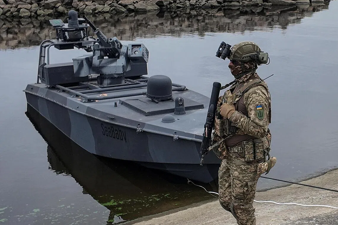 A serviceman of Ukraine's SBU security service standing next to the latest version of the country's "Sea Baby" naval drone in October 2025.