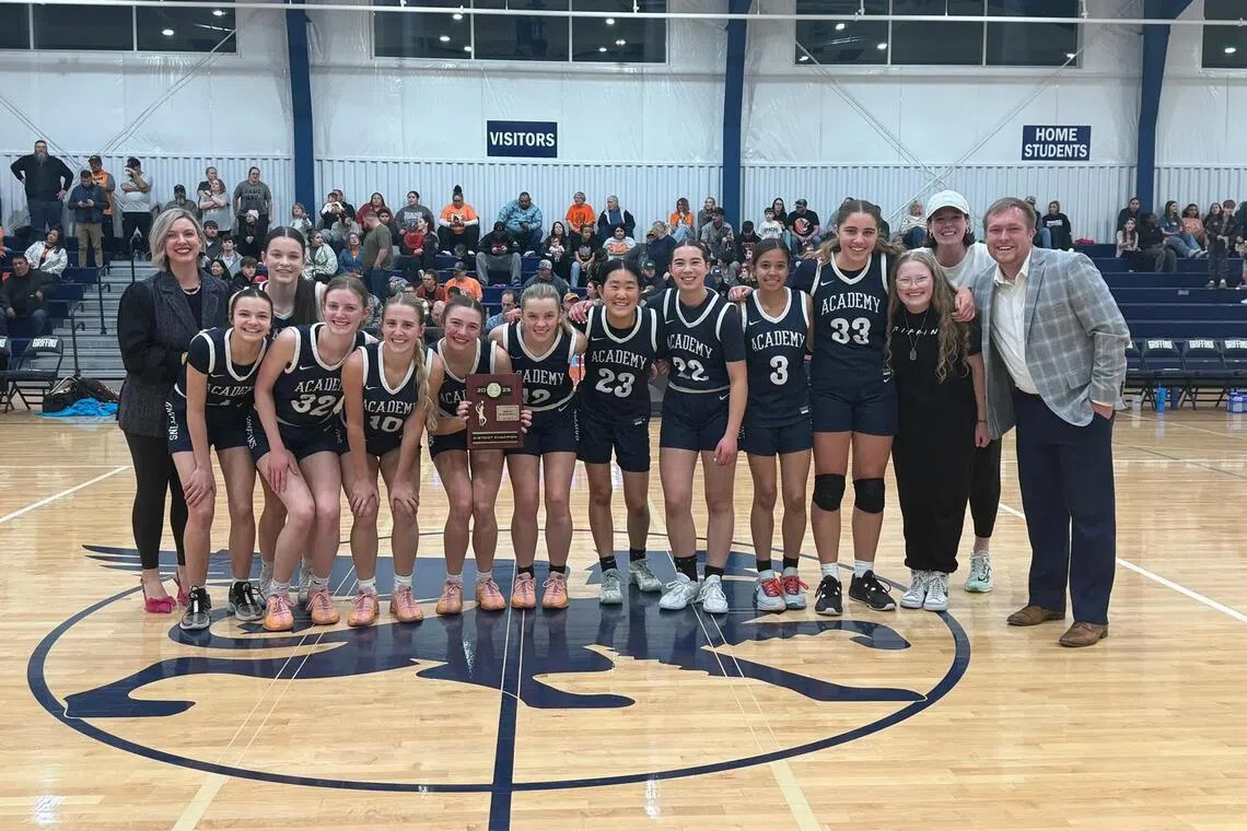 Sporting spirit: The girls high school basketball team from the Academy of Classical Christian Studies and their coach Brendan King (far right) with the trophy which they eventually returned.